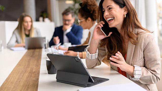 Équipe collaborant dans un bureau à l'aide d'appareils d'entreprise fournis par Bell, tels que des téléphones intelligents et des tablettes, pour une productivité accrue.