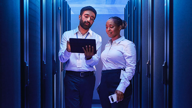 Responsables TI dans un centre de données utilisant une tablette pour simplifier la gestion des appareils grâce aux solutions de mobilité d'entreprise de Bell.