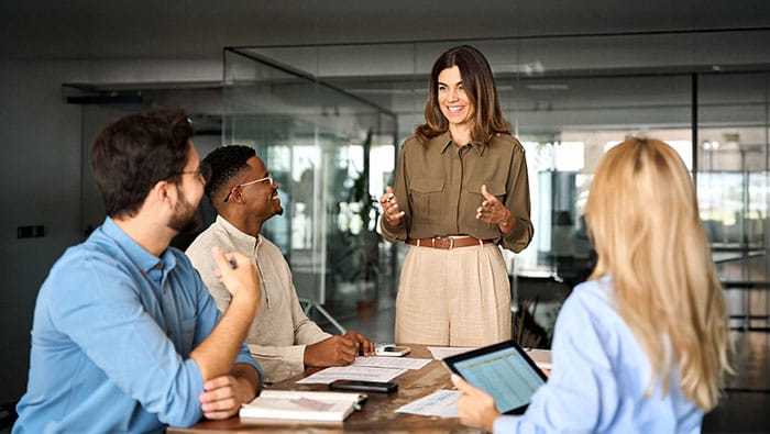 A diverse team of IoT professionals collaborates around a conference table in a modern office.