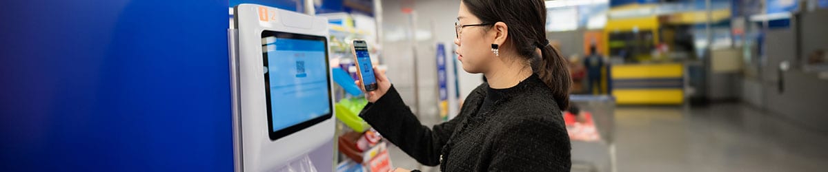 A shopper uses the CPROMO phone app to scan a QR code which will allow her to obtain her complimentary bags from the dispensing machines.